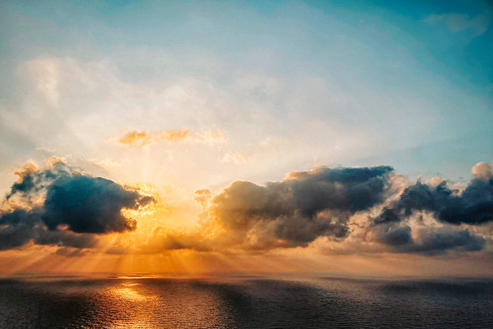 Der Sonnenuntergang über dem Meer mit dunklen Wolken, die die Sonne teilweise verdecken, ruft eine Zen-artige Ruhe hervor. Sonnenstrahlen brechen durch und werfen einen warmen Schein auf das Wasser. Der Himmel wechselt von Blau zu Orange und verwandelt diese Szene in eine innere Reise dramatischer Reflexion und ruhiger Achtsamkeit.